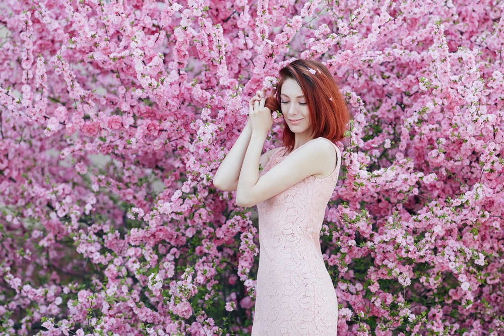 Woman fixing hair in front of a blooming tree.