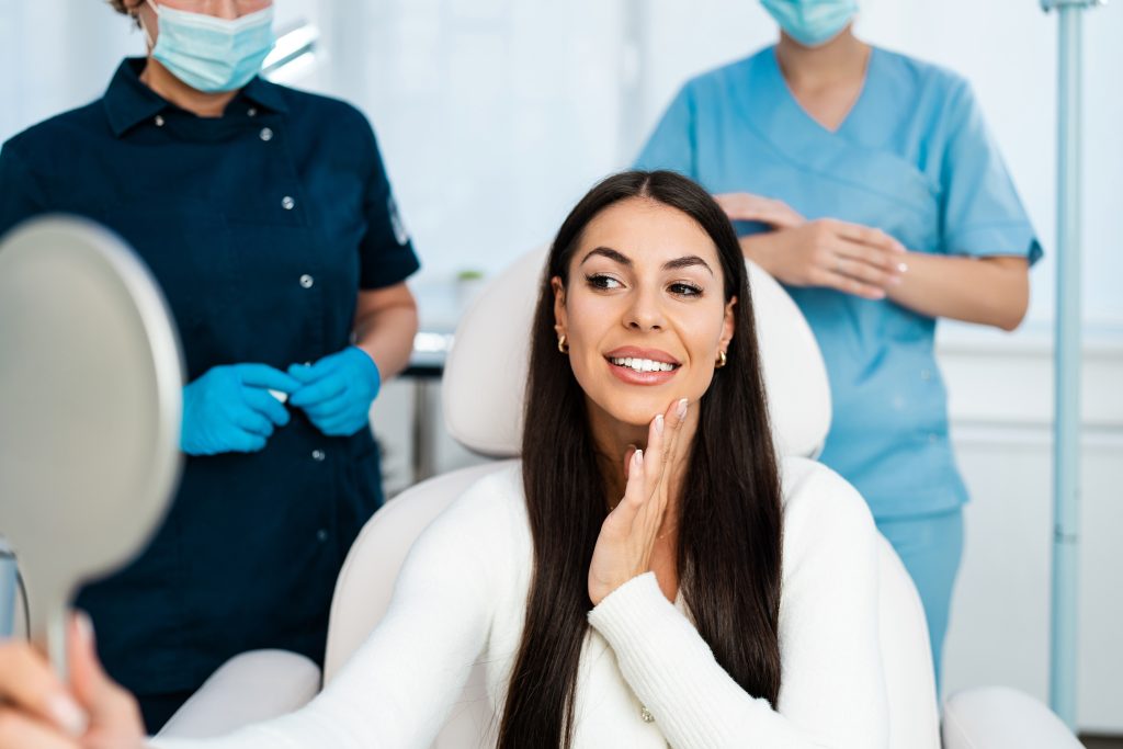 A woman in an exam room inspecting her face in the mirror